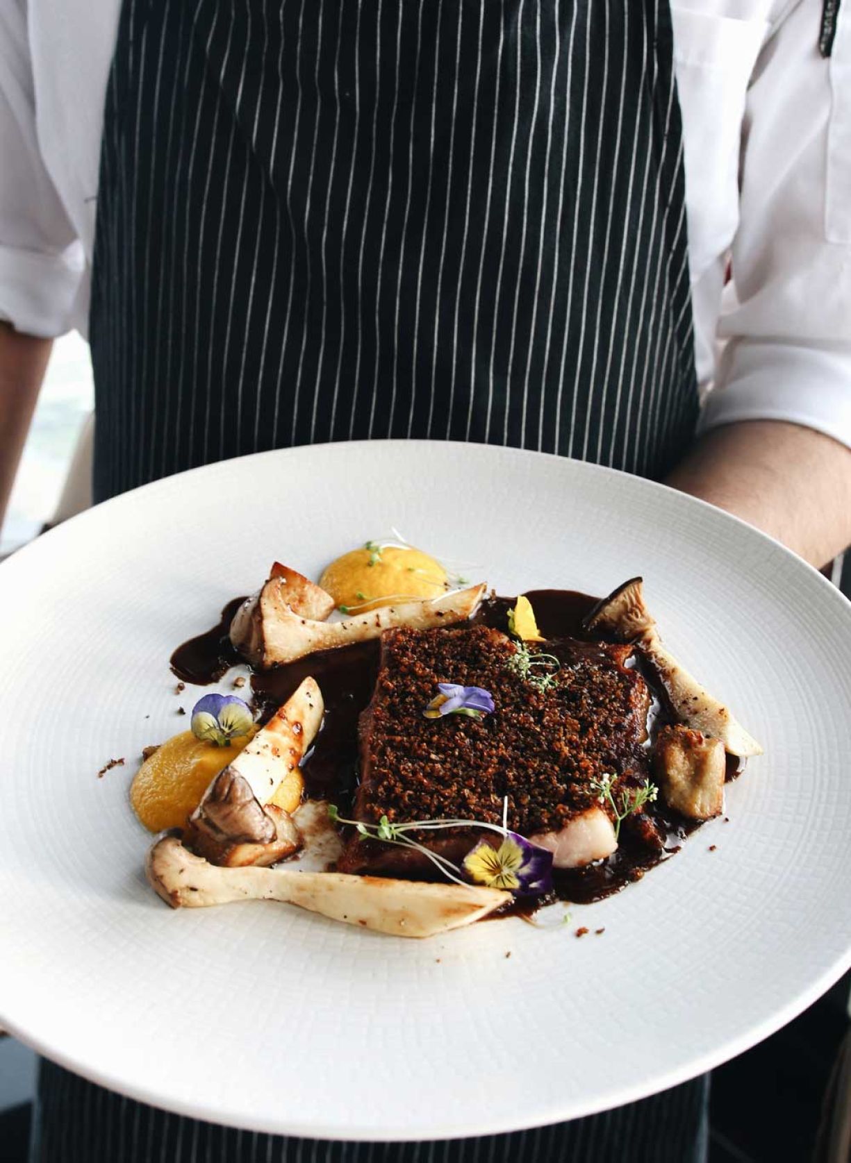 Ein Mann steht mit einem Teller voller Essen in der Hand und zeigt stolz seine Mahlzeit.