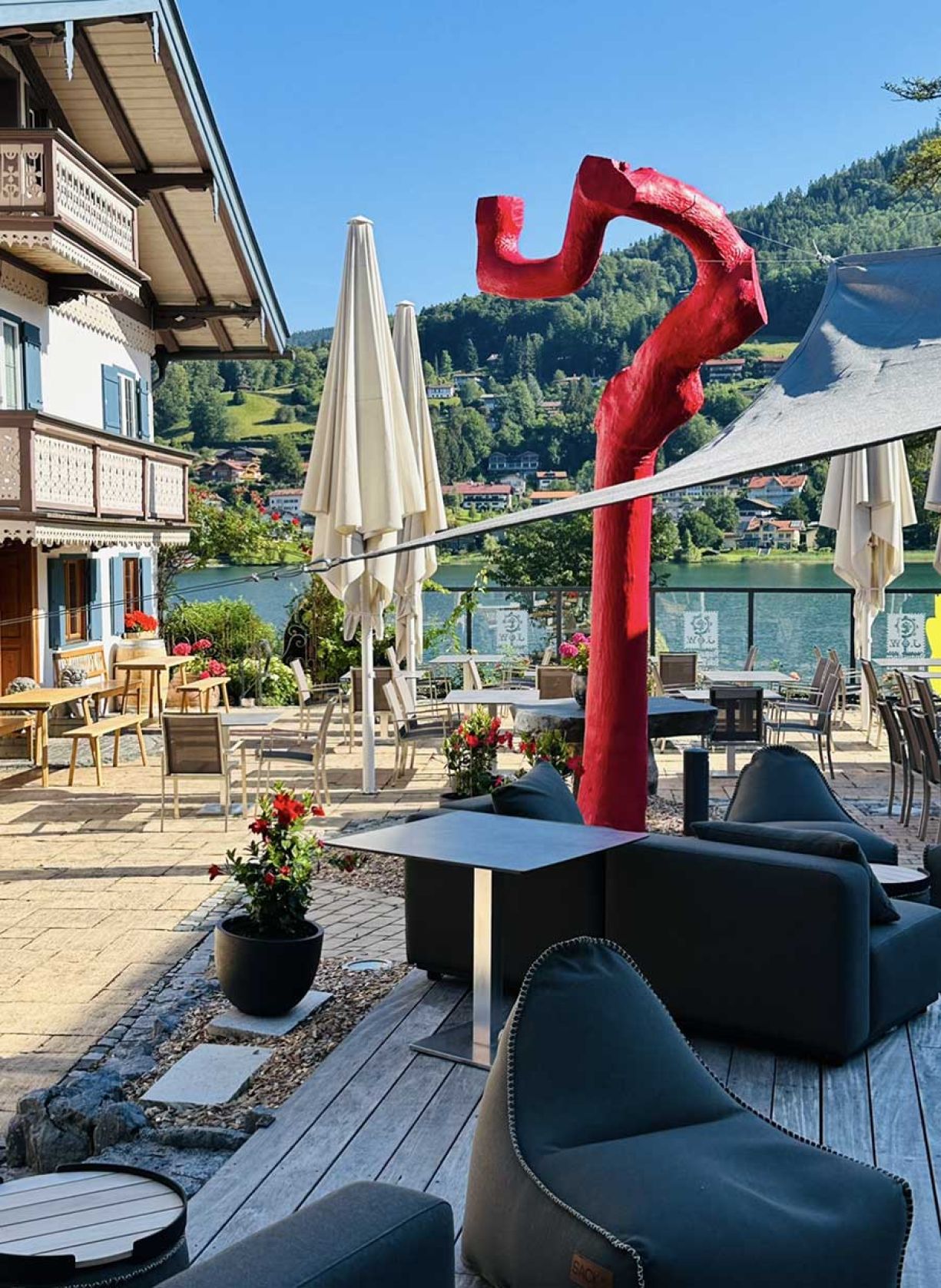 Eine Terrasse mit einer großen Skulptur und mehreren Stühlen, die eine einladende Atmosphäre schaffen.