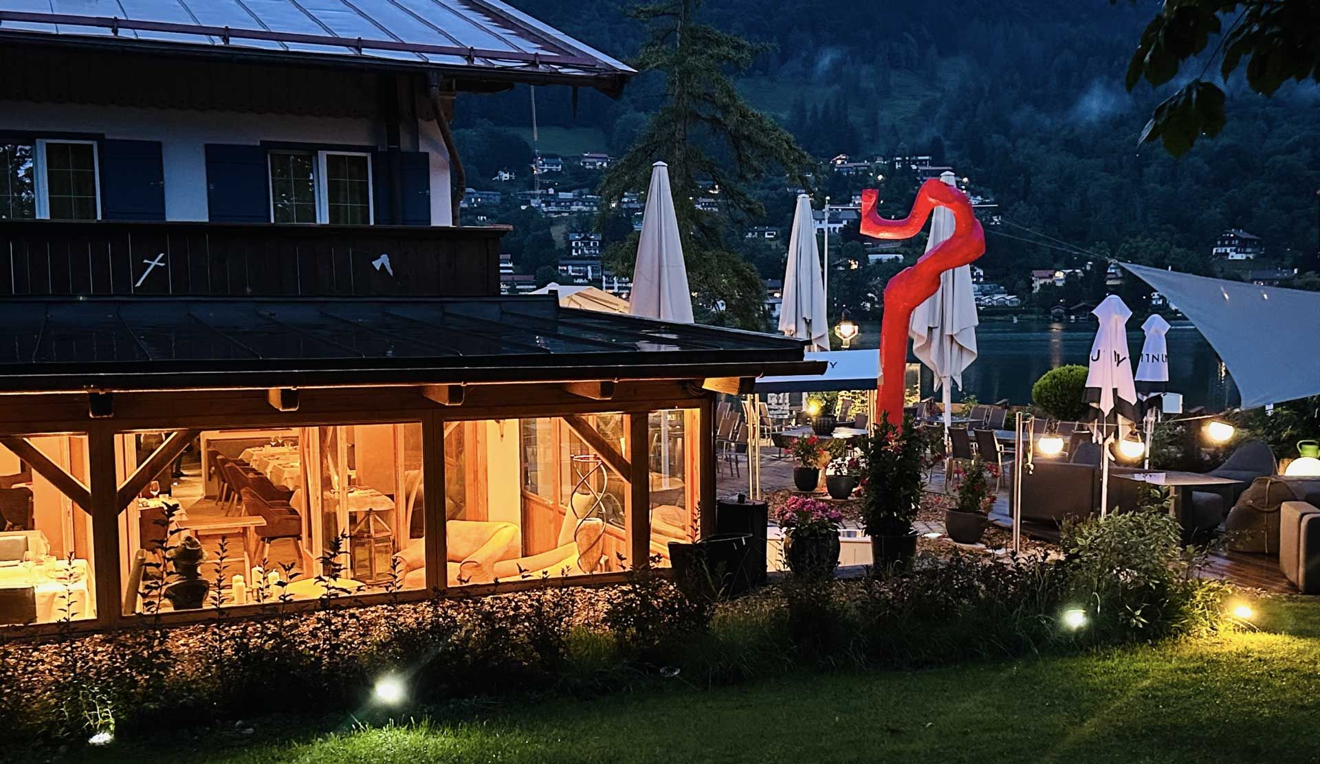 Ein Restaurant mit einem großen, beleuchteten Außenbereich bei Nacht, das eine einladende Atmosphäre schafft.